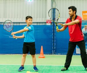 A coach showing a student how to swing a tennis racquet
