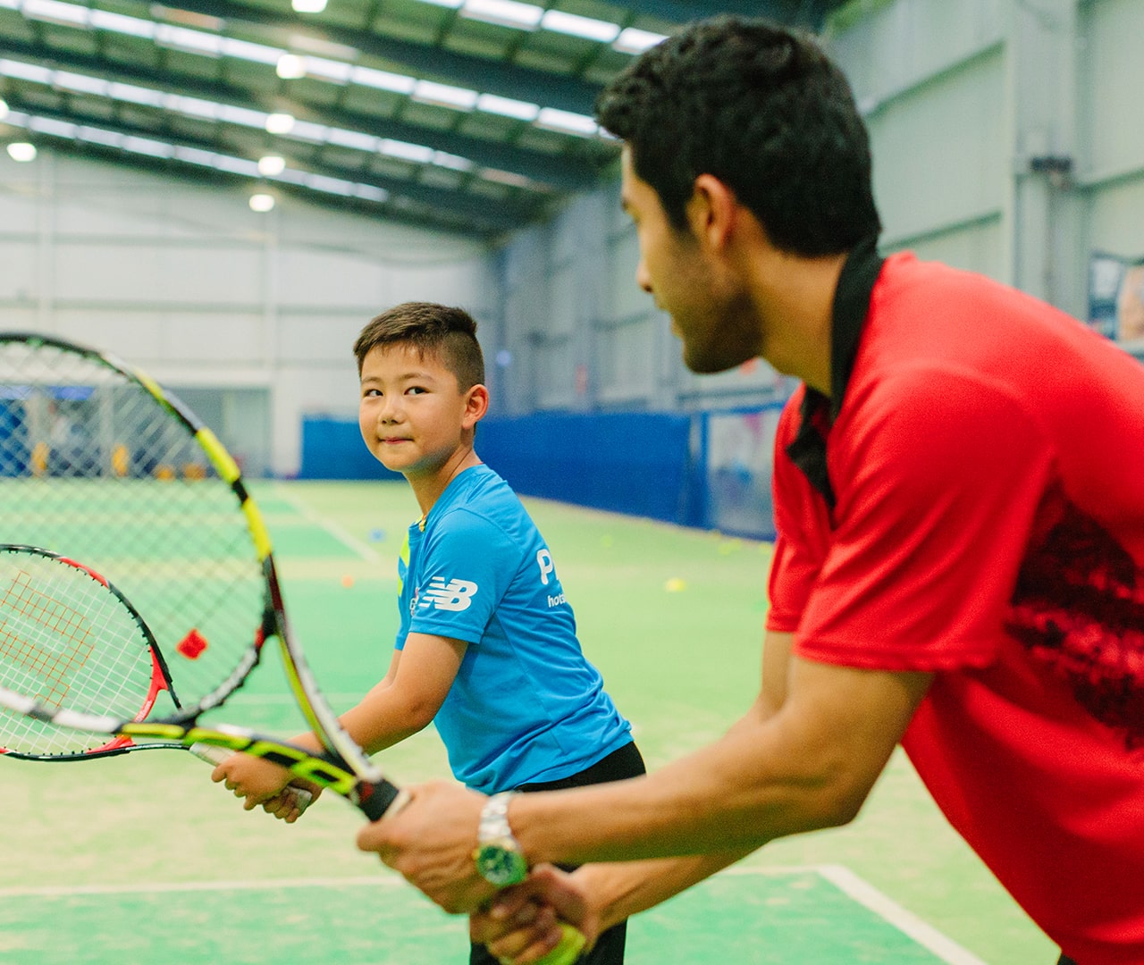 YMCA tennis coach working with young tennis player