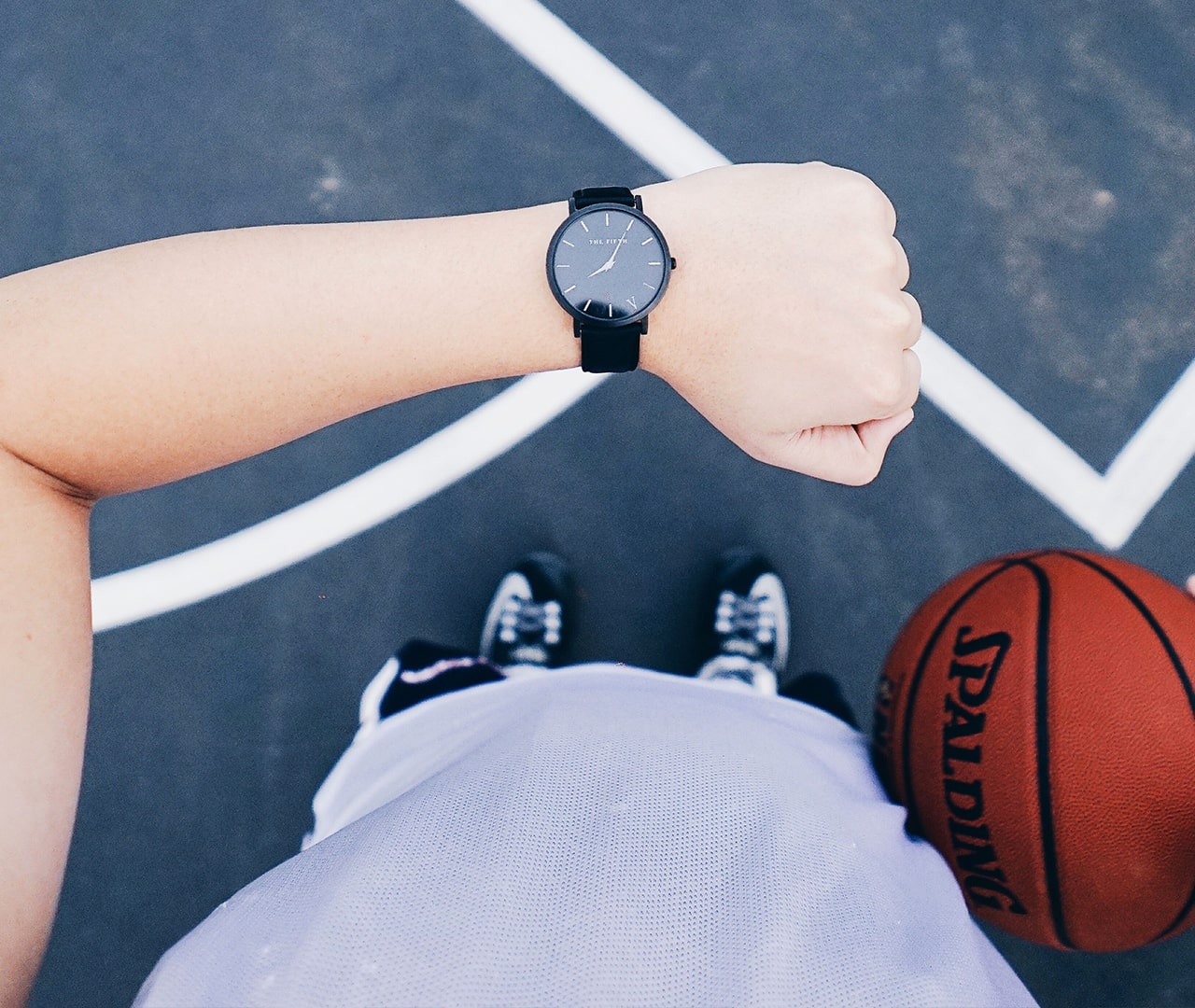Person holding a basketball and looking at their watch