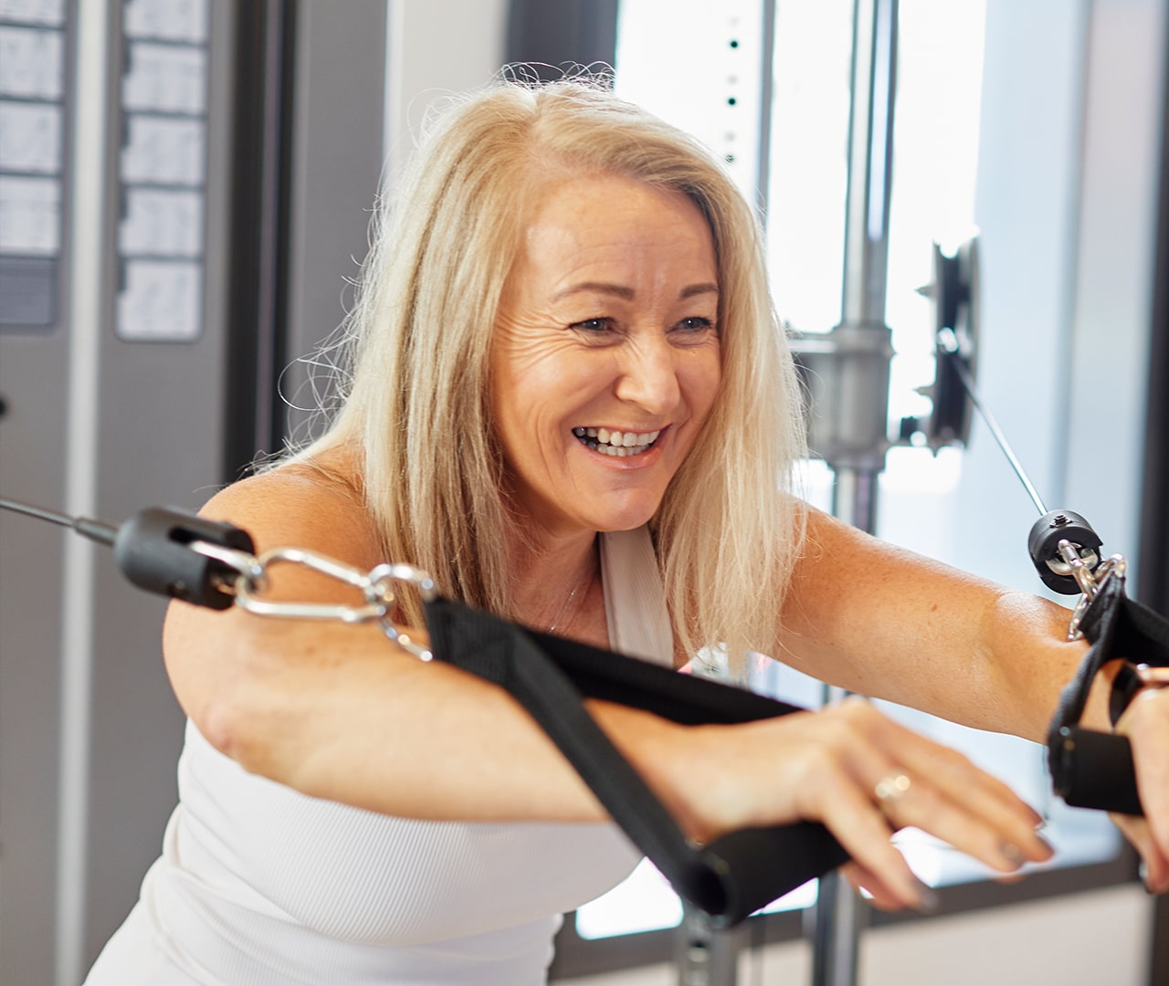 Lady smiling and using a weights machine