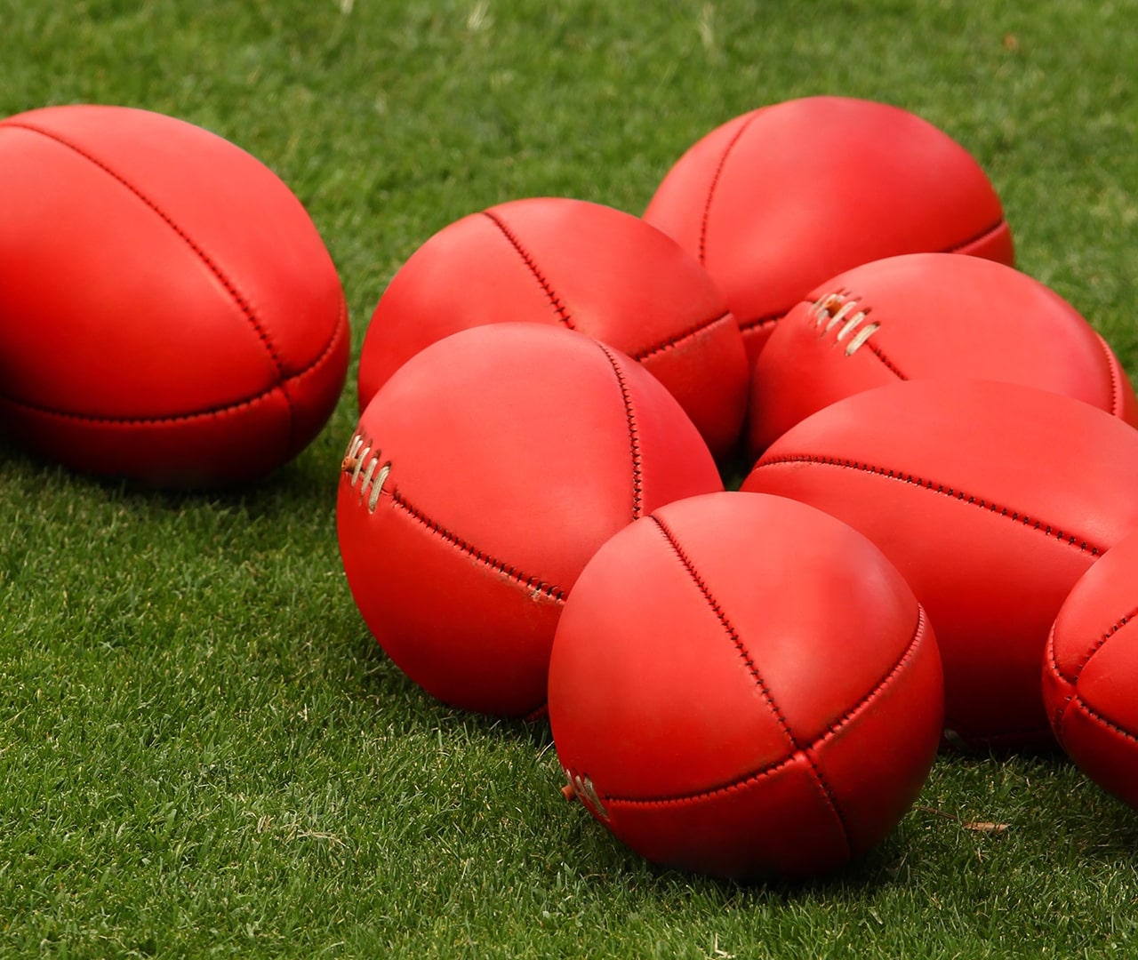 Red AFL footballs on the grass