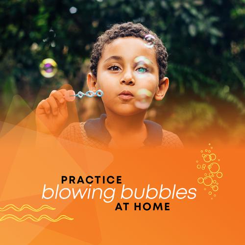 A young child blowing bubbles using bubble mixture