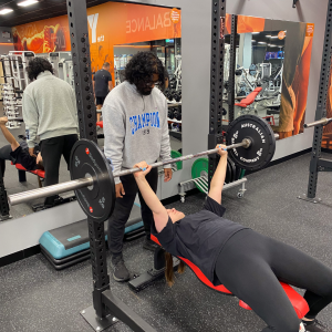 Male spotting women lifting weights